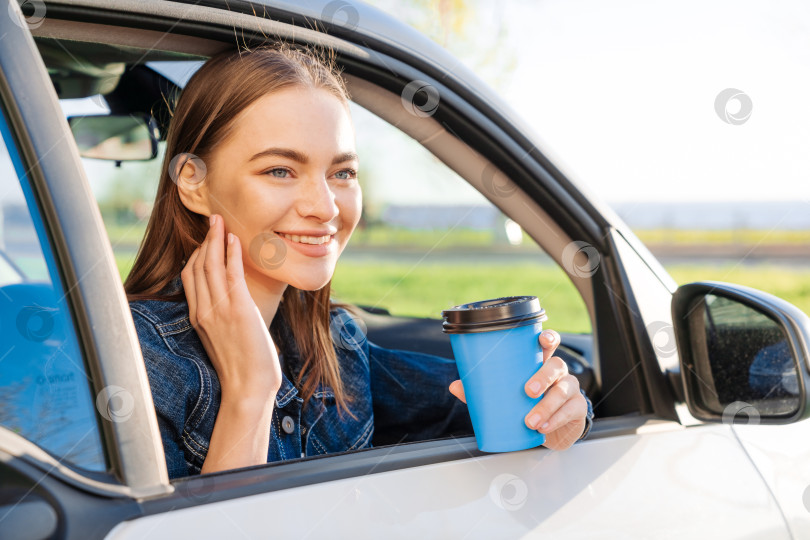Скачать Красивая молодая женщина ехала по дороге в автомобиле, попивая кофе из одноразовой фотосток Ozero