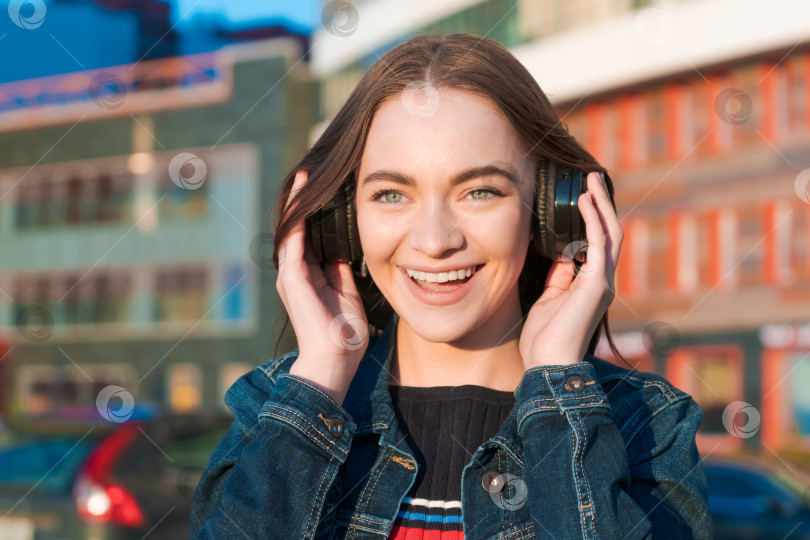 Скачать Красивая молодая девушка слушает музыку в наушниках, уличный стиль, на открытом воздухе фотосток Ozero