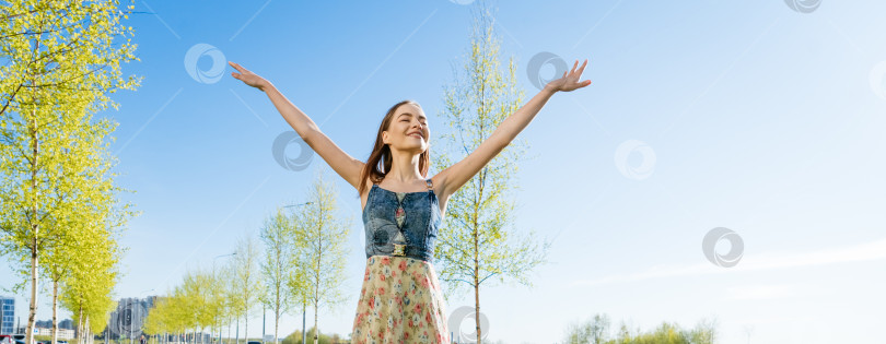 Скачать Привлекательная счастливая молодая женщина в длинном цветастом платье с развевающимися волосами наслаждается свободным фотосток Ozero