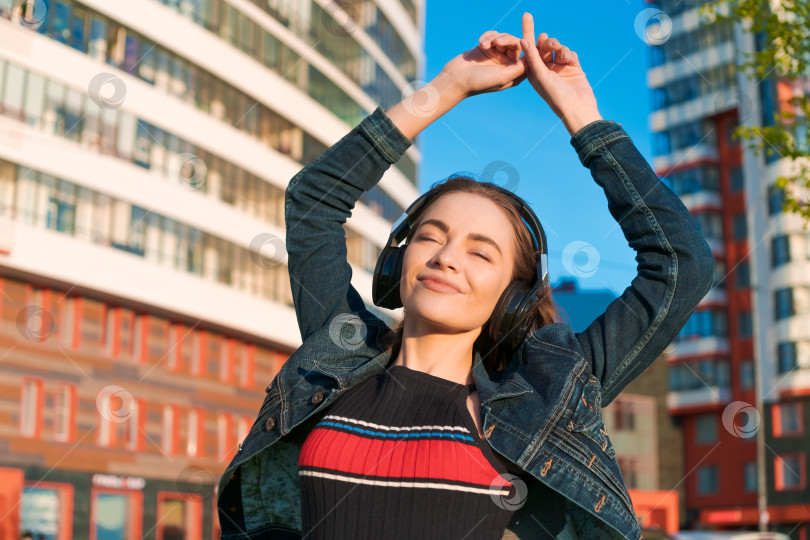Скачать Красивая молодая девушка слушает музыку в наушниках, уличный стиль, на открытом воздухе фотосток Ozero