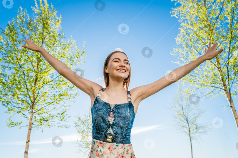 Скачать Привлекательная счастливая молодая женщина в длинном цветастом платье с развевающимися волосами наслаждается свободным фотосток Ozero