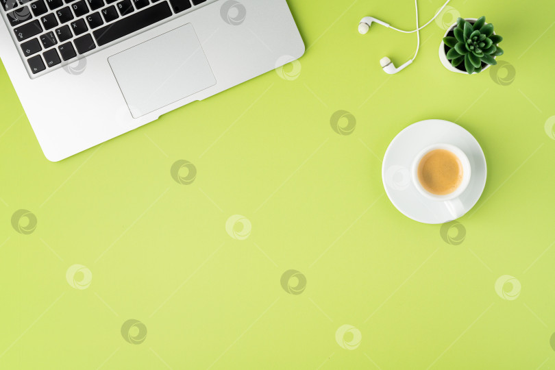 Скачать Горизонталь металлической клавиатуры ноутбука, белых наушников и кофейной чашки на светло-зеленом фоне фотосток Ozero