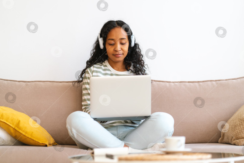 Скачать Посещаю онлайн-занятия из дома. Афроамериканский студент работает за ноутбуком, слушает лекцию фотосток Ozero