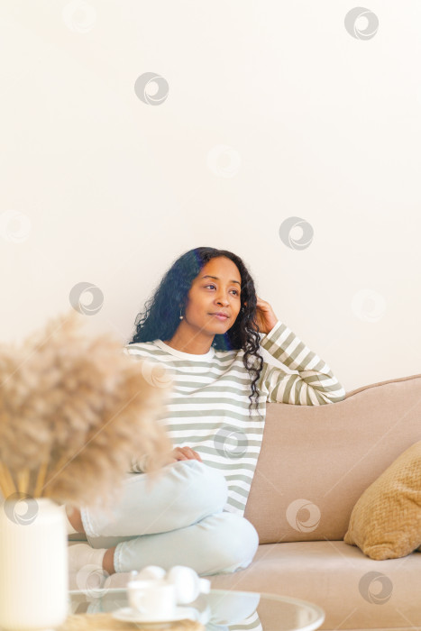 Скачать Задумчивая афроамериканка, сидящая на диване в гостиной и мечтающая, избирательная сосредоточенность фотосток Ozero