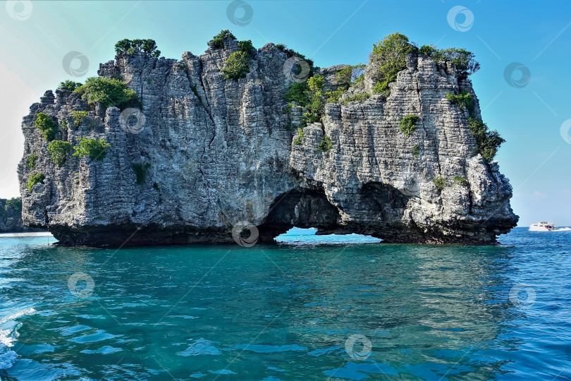 Скачать Остров с крутыми склонами возвышается над прозрачной аквамариновой водой. фотосток Ozero