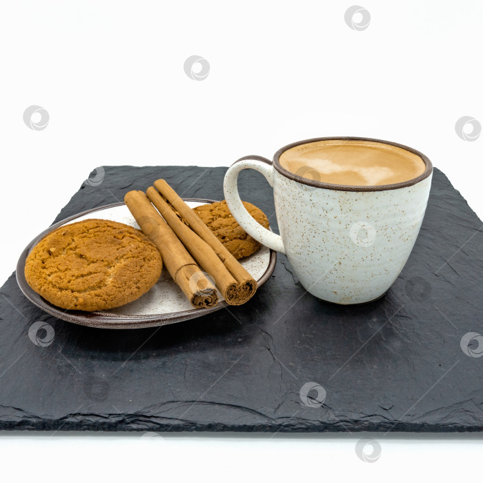 Скачать На черной каменной плитке стоит чашка кофе и блюдце с печеньем и палочками корицы. фотосток Ozero