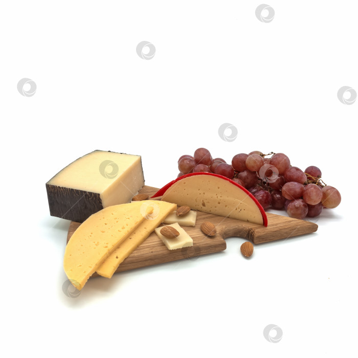 Скачать На деревянной треугольной разделочной доске лежат несколько видов сыра, миндальные семечки фотосток Ozero