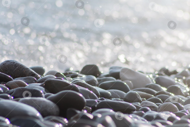 Скачать Морская галька, камни и вода, расфокусированное солнце освещает природный фон боке. Фон из натуральных пляжных камней, обои с мягким фокусом. фотосток Ozero