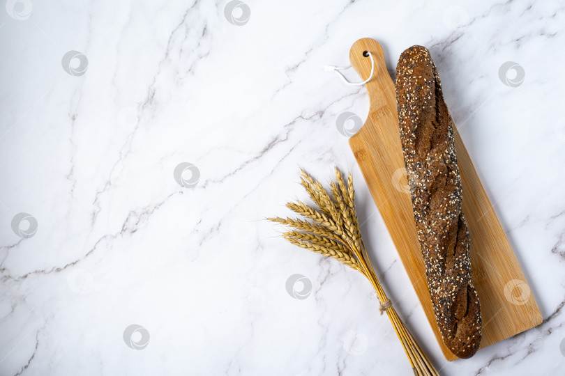 Скачать Свежеприготовленный ржаной багет с хрустящей корочкой и колосьями ржи и пшеницы фотосток Ozero