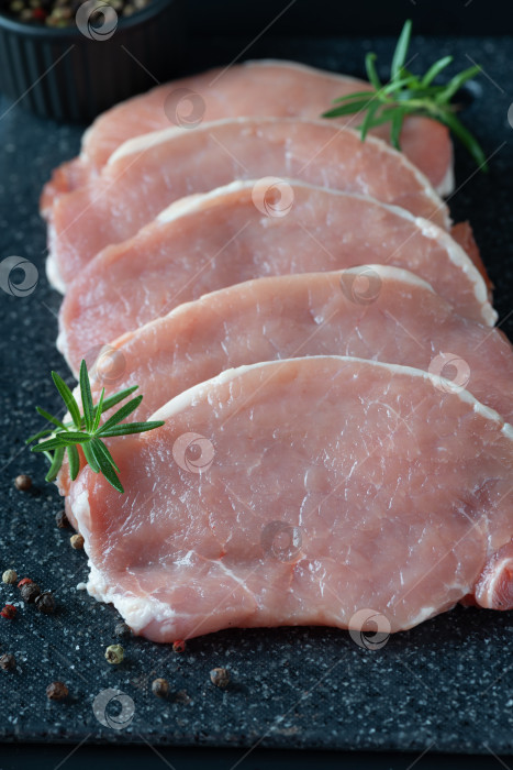 Скачать Нарезать сырое свиное мясо ломтиками на темной разделочной доске фотосток Ozero