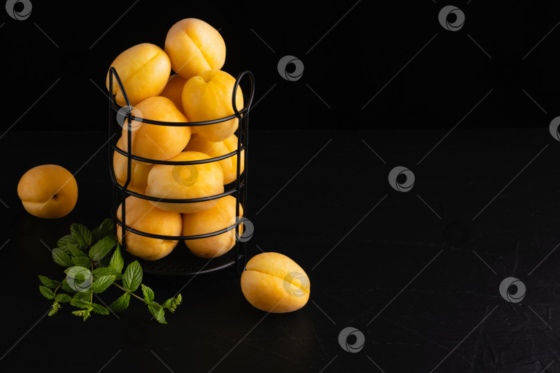 Скачать Свежие абрикосы в корзинке на черном деревянном столе фотосток Ozero