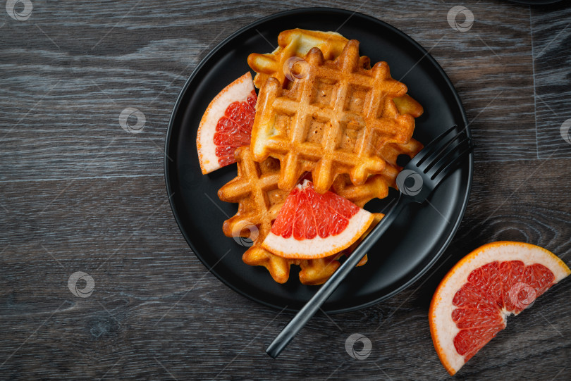 Скачать Вафли и грейпфрут в черной тарелке на деревянном столе фотосток Ozero