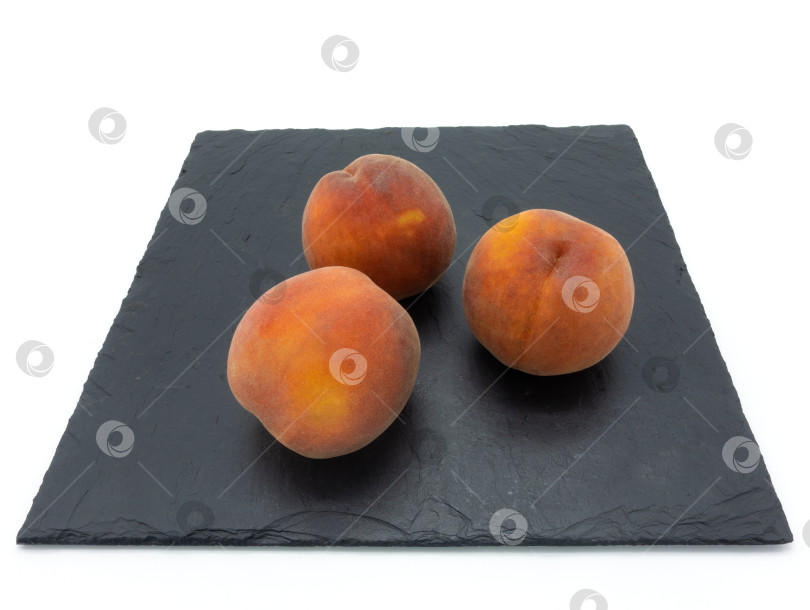 Скачать Три целых спелых персика лежат на каменной плите. фотосток Ozero
