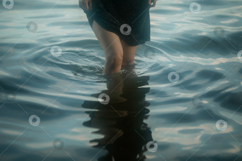 Скачать Девушка в платье идет по колено в воде. Женские ноги крупным планом. фотосток Ozero