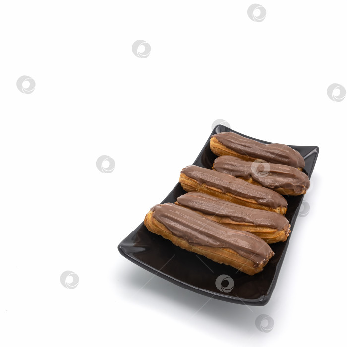 Скачать Пять свежих эклеров с шоколадной глазурью лежат на черной прямоугольной тарелке фотосток Ozero