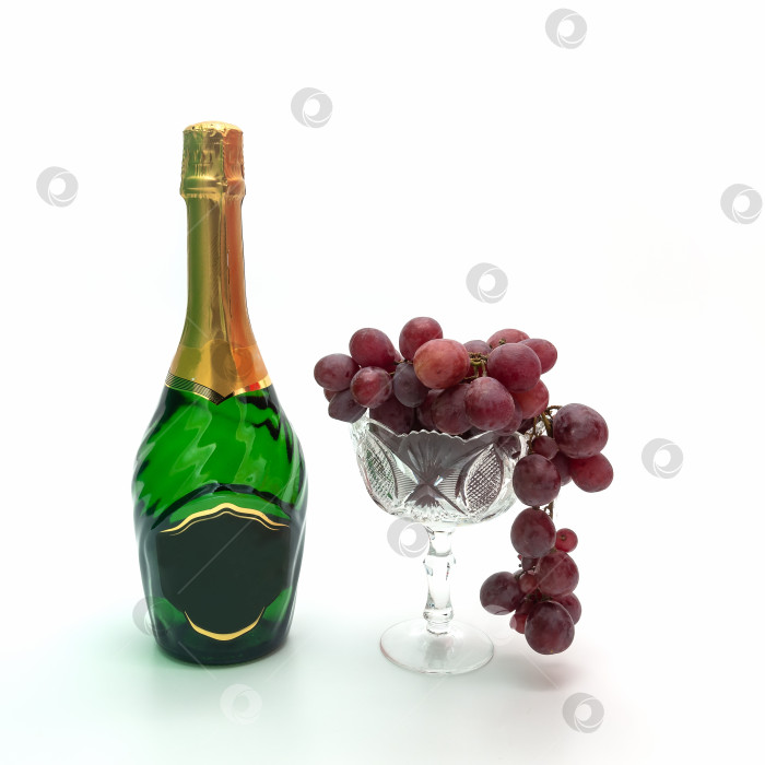 Скачать Вино и виноград. Зеленая бутылка шампанского стоит рядом с граненой хрустальной вазой с виноградом. фотосток Ozero