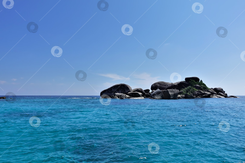 Скачать На фоне бирюзового Андаманского моря и лазурного неба - маленький скалистый остров. фотосток Ozero