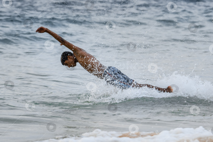 Скачать Занзибар, Танзания, 09 декабря 2021 года: Рыбак из Занзибры ныряет в океан. Брызги летят с его волос. Мускулистый африканский мужчина фотосток Ozero