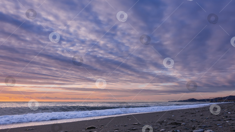 Скачать Закат. В небе бело-голубые облака, оранжевое свечение. На пляже есть песок и галька. фотосток Ozero