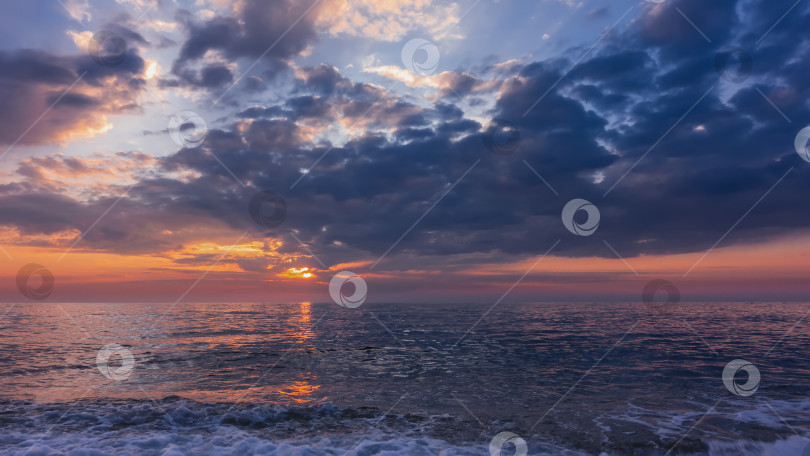 Скачать Закат. Солнце светит сквозь голубые облака.  Солнечная дорожка на блестящей поверхности моря. фотосток Ozero