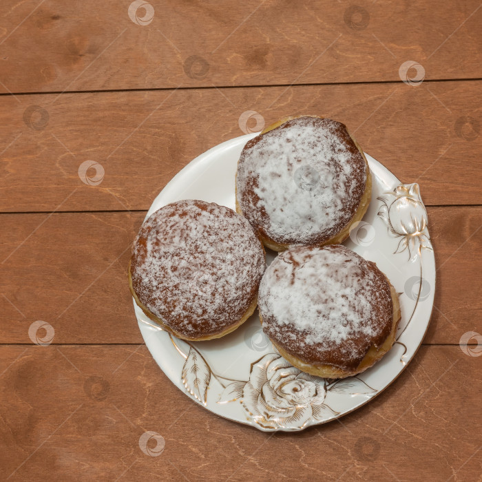 Скачать Три пончика, посыпанные сахарной пудрой, лежат на тарелке. фотосток Ozero