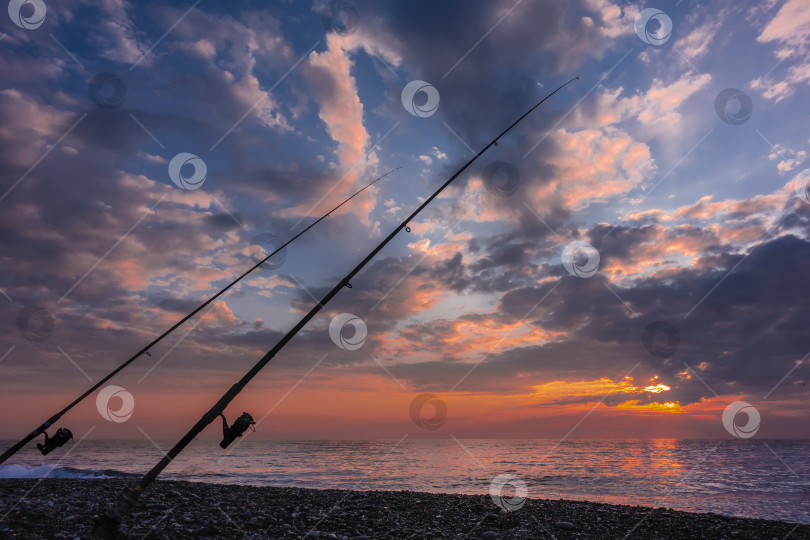 Скачать Две удочки на пляже, на фоне прекрасного закатного неба. фотосток Ozero