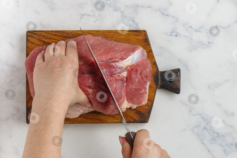 Скачать Женские руки нарезают органическое сырое свиное мясо на разделочной доске на м фотосток Ozero