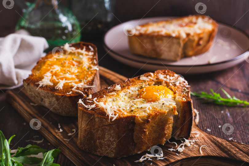 Скачать Хлеб, запеченный с яйцом и сыром на разделочной доске фотосток Ozero