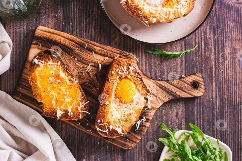 Скачать Хлеб, запеченный с яйцом и сыром на разделочной доске, вид сверху фотосток Ozero