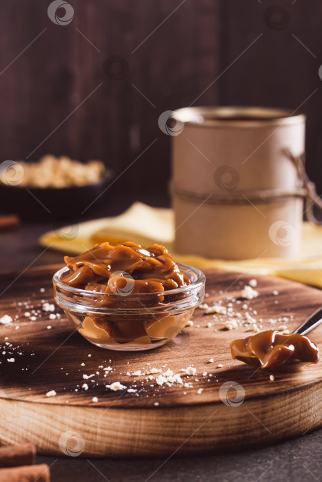 Скачать Вареное сладкое сгущенное молоко в миске и ложкой на столе вертикально фотосток Ozero