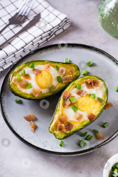 Скачать Яйцо, запеченное в авокадо, посыпанное беконом и зеленью, на тарелке v фотосток Ozero