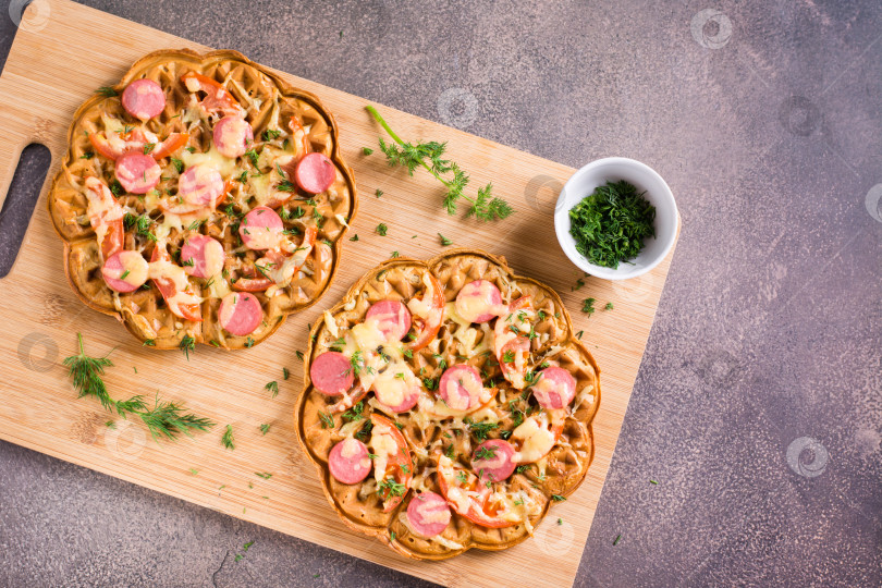 Скачать Вафельная пицца с помидорами, сосисками, сыром и зеленью на деревянной сковороде фотосток Ozero