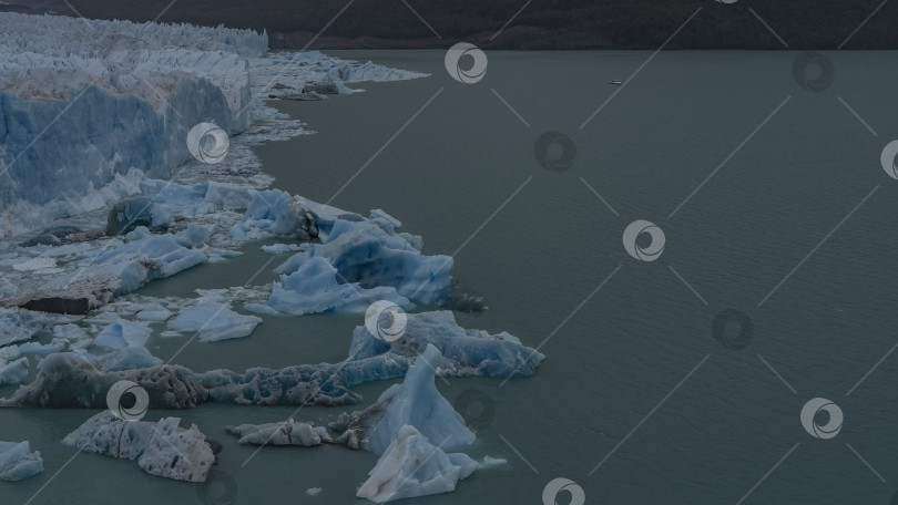Скачать Стена голубого льда возвышается над водой. Отколовшиеся айсберги плавают в бирюзовом озере. фотосток Ozero