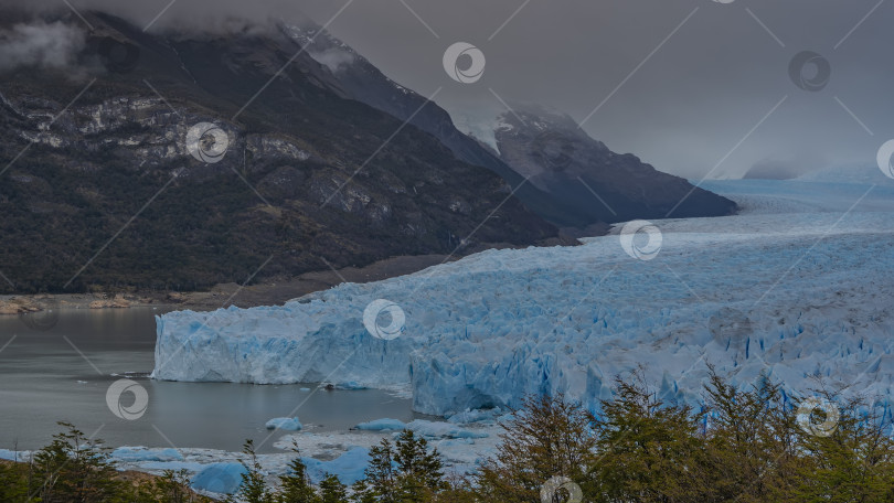 Скачать Невероятный голубой ледник Перито-Морено простирается до горизонта между горами. фотосток Ozero