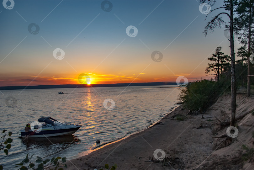 Скачать 19.07.2013: Россия, Ульяновск, Волга, остров Пальцинский. Лодка, припаркованная недалеко от острова на фоне заката фотосток Ozero