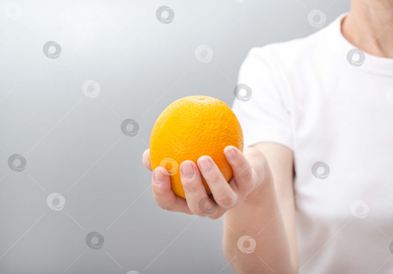 Скачать Женская рука держит апельсин. фотосток Ozero
