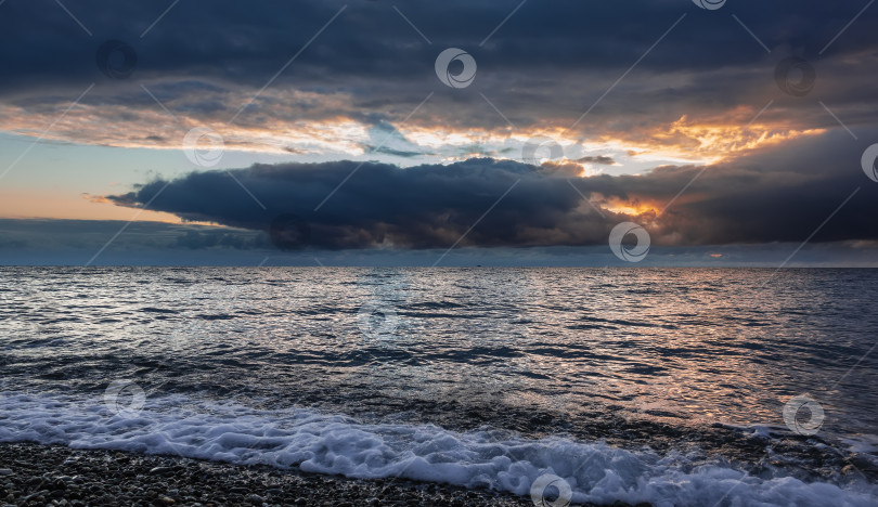 Скачать Тревожный осенний закат над морем. Солнце прячется за темными облаками. фотосток Ozero