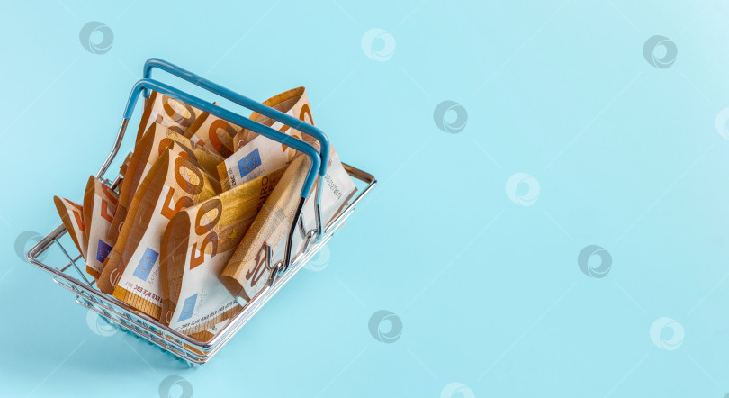Скачать Металлическая корзина из супермаркета, наполненная банкнотами по пятьдесят евро. фотосток Ozero