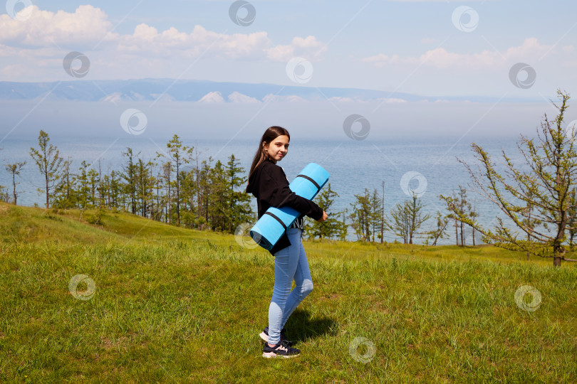 Скачать Молодая девушка собирается заняться йогой или фитнесом на природе. фотосток Ozero