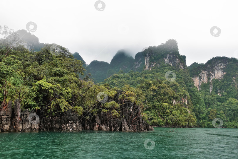 Скачать На озере Чоу Лан идет дождь. Острова покрыты тропической растительностью. Таиланд фотосток Ozero