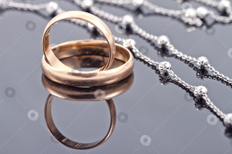 Скачать Золотые обручальные кольца и элегантная серебряная цепочка фотосток Ozero