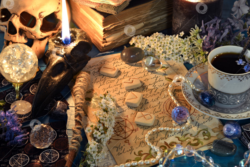Скачать Горящая черная свеча, череп, руны и кристаллы на алтарном столе ведьмы. Оккультный, эзотерический и гадательный натюрморт. Мистический фон с винтажными предметами фотосток Ozero