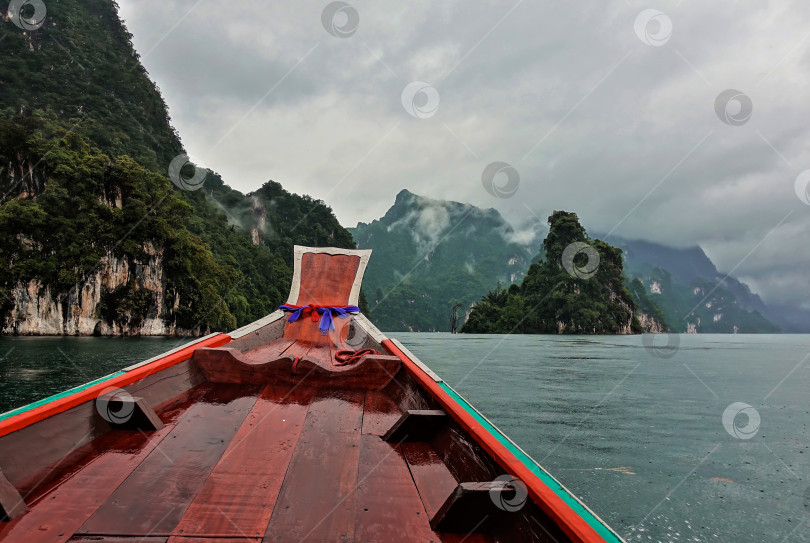 Скачать Тайская длиннохвостая лодка плывет по озеру.  Озеро Чео Лан, Таиланд фотосток Ozero