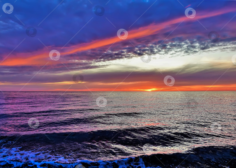 Скачать Яркий закат над морем. Темно-синие облака выделены алым цветом. фотосток Ozero