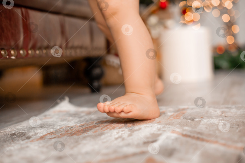 Скачать Ножки малыша на деревянном полу рядом с рождественской елкой, крупный план фотосток Ozero