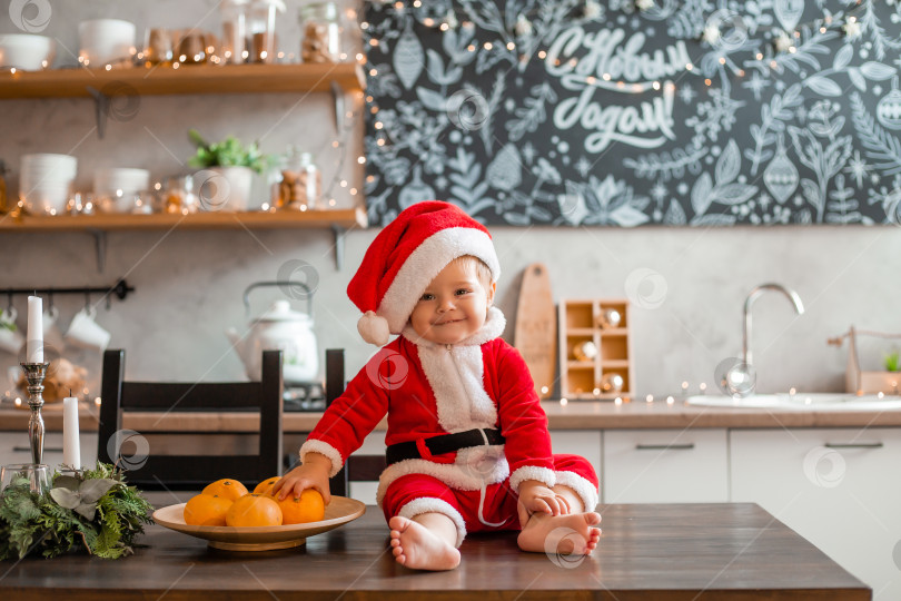 Скачать Малыш Санта сидит на кухне дома, надпись на графической доске на русском языке "с новым годом"! фотосток Ozero