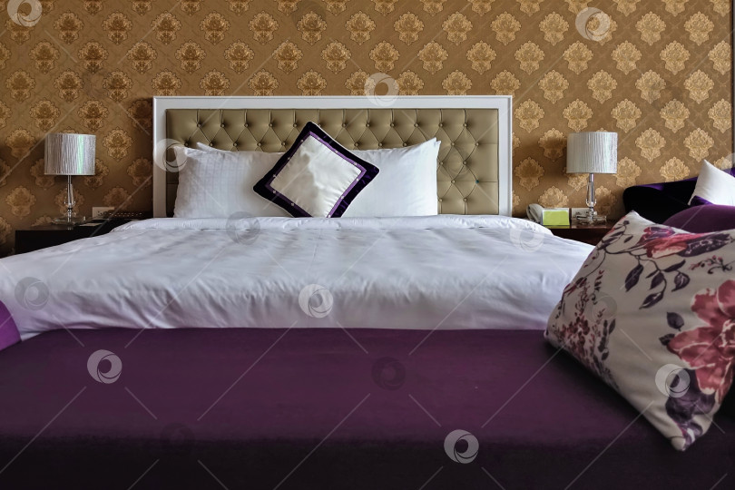 Скачать Интерьер спальни. Большая двуспальная кровать с белыми простынями и подушками. фотосток Ozero