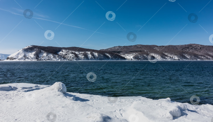 Скачать Никогда не замерзающий исток реки Ангары. Голубая вода течет между заснеженными берегами. фотосток Ozero