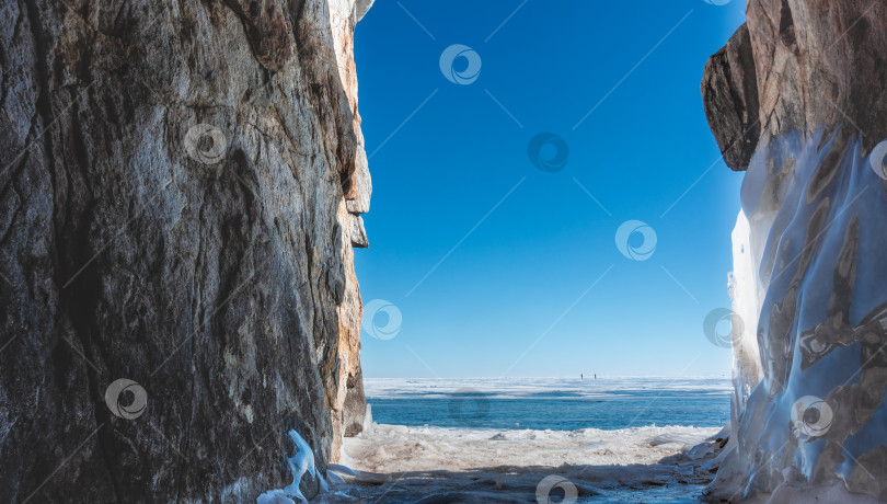 Скачать Между двумя высокими обледенелыми скалами есть проход к озеру, покрытому голубым льдом и снегом. фотосток Ozero