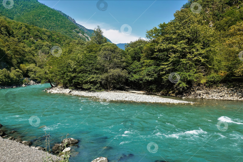 Скачать Бирюзовая река течет между зелеными горными склонами. Летний солнечный день. Абхазия фотосток Ozero